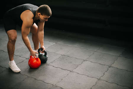 Strong muscular man with perfect beautiful body wearing sportswear lifting heavy free weights during sport workout training in modern dark gym. Concept of healthy lifestyle.の写真素材