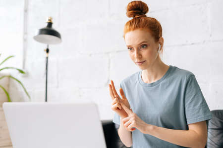 Redhead young businesswoman freelancer counting using fingers during video call online chat on...
