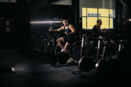 Athletic strong man exercising on simulator during sport workout in modern gym. Concept of healthy lifestyle.の写真素材