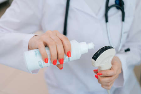 Close-up of female doctor applying the ultrasound gel to the scanner for performing ultrasound of belly of pregnant woman in medical clinic. Concept of happy and healthy childbearing.の写真素材