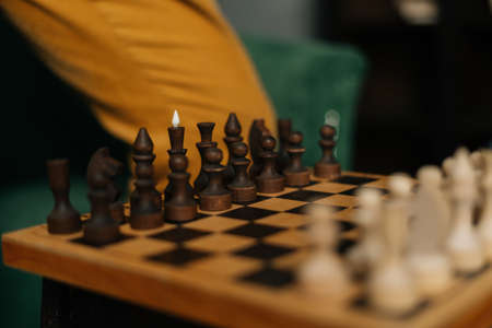 Side view of chessboard with placed chess pieces on black old vintage table, focus on background....