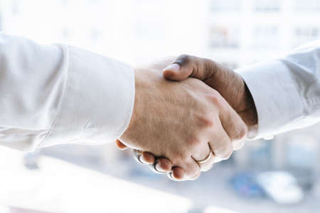 Close-up handshaking of two colleagues African business man and Caucasian businessman background of...