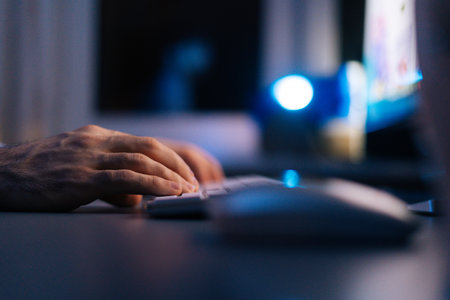 Close-up hands of unrecognizable man writing message to social network. Side view of computer hacker typing code virus pc on wireless keyboard late night working. Concept of remote working.の写真素材