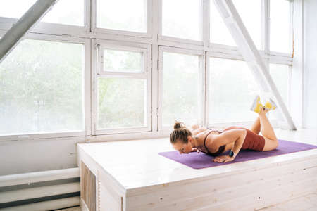 Muscular fit young woman with perfect athletic body wearing sportswear doing push-ups exercises at...