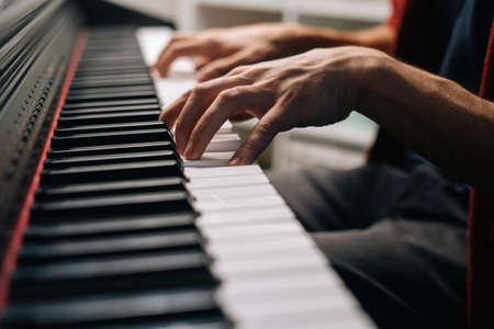 Close-up hands of unrecognizable musician man playing on synthesize at home studio during lesson. Closeup of pianist male playing on digital piano in living room. Concept of music education.の写真素材