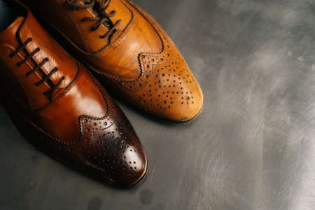 Close-up top view of old light brown leather shoe and repaired shiny shoes after restoration working. Concept of cobbler artisan repairing and restoration work in shoe repair shop.の写真素材