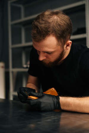 Portrait of bearded shoemaker cleaning old leather shoes for later restoration, close-up. Concept of cobbler artisan repairing and restoration work in shoe repair shop.の写真素材