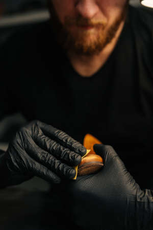 Close-up front view of shoemaker wearing black latex gloves cleaning old light brown leather shoes with rag for later restoration. Concept of cobbler artisan repairing and restoration work.の写真素材
