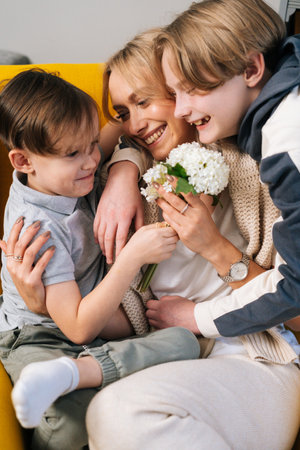 Close-up of two cheerful little funny kid child sons congratulating happy young mom with mothers day...