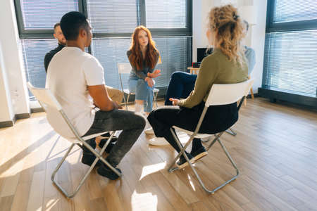 Front view of confident young redhead businesswoman talking and discussing new ideas with creative...