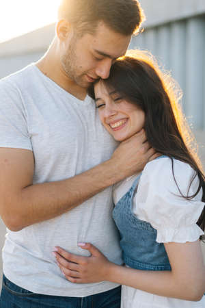 Vertical portrait of beautiful romantic young couple in love hugging while man touching neck of...