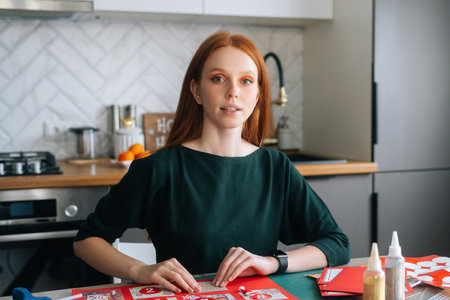 Medium shot portrait of attractive young woman gluing envelopes on board with gifts for children...