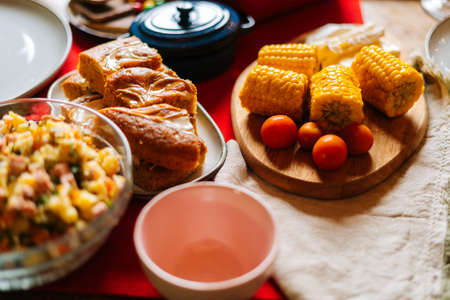 Close-up top view of delicious boiled yellow corn on feast dinner table during holiday friendly family party, selective focus. Concept of celebration New Year, Christmas, wedding, birthday.の写真素材