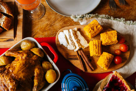 Close-up top view of delicious boiled yellow corn and roasted homemade thanksgiving turkey on Christmas dinner feast table during holiday friendly family party, no people, selective focus.の写真素材