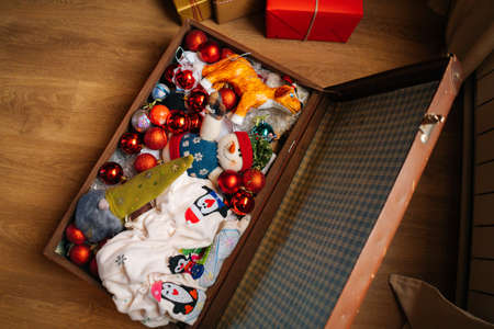 High-angle view of various festive Christmas toys and colorful balls lying in old family suitcase box, selective focus. Preparing for xmas, new year and winter holidays, happy mood.の写真素材
