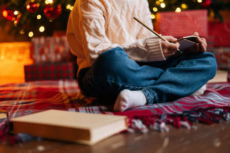 Close-up cropped shot of unrecognizable happy little child girl writing letter to Santa Claus...