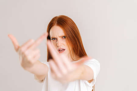 Close-up portrait of furious young woman showing middle fingers on both arms, gesture of disrespect and hate, doing bad expression. Rude and rude female showing middle finger looking at camera.の写真素材