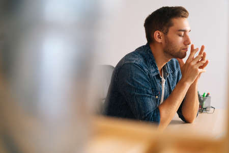 Side view of frustrated handsome freelance programmer male in wireless earphone working on laptop computer sitting at desk at home office. Concept of distance remote work, education.の写真素材