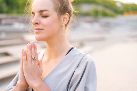 Close-up face of calm attractive young woman practicing yoga performing namaste pose with closed...