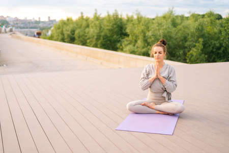 Portrait of calm Caucasian young woman practicing yoga performing namaste pose with closed eyes...