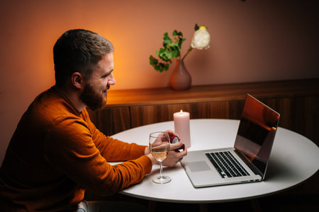 Cheerful young man making video call using laptop computer presenting ring and making remote marriage proposal sitting at table. Loving boyfriend making distant proposal for marriage, marry me.の写真素材
