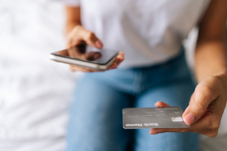 Close-up cropped shot of unrecognizable female customer entering credit card code to pay gifts, online shopping on smartphone. High-angle view of shopper internet purchases or payments via phoneの写真素材