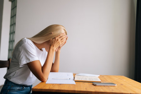 Side view of tired young woman massaging temples, suffering from headache after paperwork, sitting...