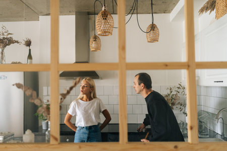 Remote view of angry husband scolding, raising voice, yelling at ignoring young girlfriend wife standing in kitchen room. Young Caucasian couple quarrelling yelling at home. Concept of family problemsの写真素材