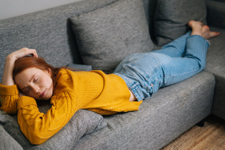 High-angle view of peaceful young woman with serene face relax at home lying down in comfortable...