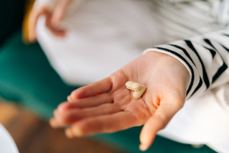 Close-up high-angle view of pill in female hand. Close up of unrecognizable young woman takes medicines. Concept of daily norm of vitamins, effective drugs, modern pharmacy for body and mental health.の写真素材