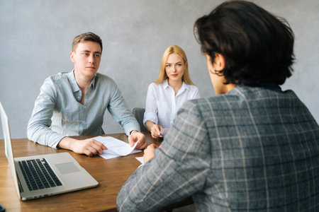 Back view of unrecognizable male applicant introducing during job interview, talking about working experience, recruiters hr managers interviewing listening to candidate, considering cv resume.の写真素材
