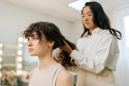 Closeup side view of young beautiful woman having hair cut at female hairstylist in modern beauty...