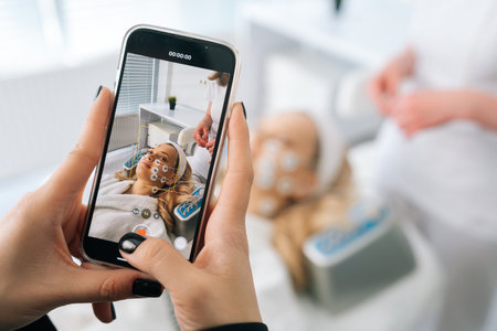 Recording video or take photo on phone of hardware electro myostimulation procedure in clinic of aesthetic medicine. Hardware electro myostimulation procedure at beauty spa salon.の写真素材