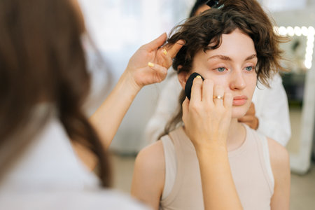 Close-up cropped shot of unrecognizable female beauty specialist using blending sponge applying...