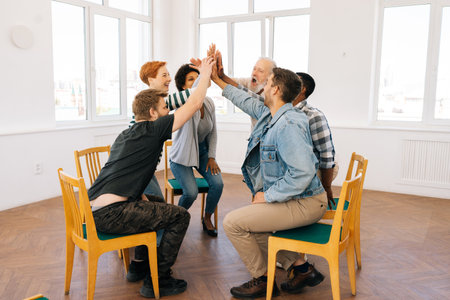 Diverse happy multicultural and different ages people reach hands to give high five sitting on...