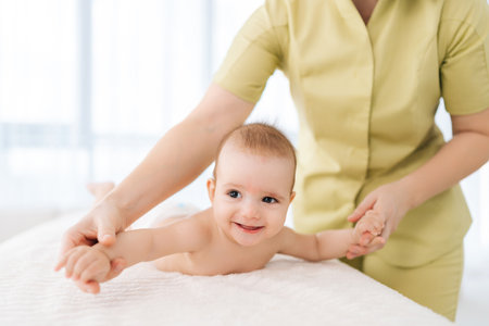 Cropped shot of unrecognizable pediatric masseur with cute baby boy doing exercise simple exercises to make baby bones and muscles stronger. Portrait of laughing newborn infant lying on bed.の写真素材