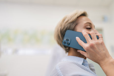 Closeup of elegant middle-aged woman enjoy pleasant conversation distantly with grown up children or friend. 50s female holding mobile phone ordering goods online using easy quick services concept.の写真素材