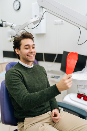 Vertical portrait of handsome cheerful young male patient smiling into mirror looking at healthy...