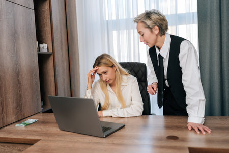 Female angry boss reprimands incompetent woman employee for bad work result, decreasing financial stats in report, scolds for inefficiency. Executive manager dissatisfied with declining projectの写真素材