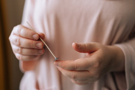 Close-up hands of unrecognizable female artisan craftperson holding special tool to mixing dry soy wax for creating candle building mixture. Process of making handmade natural scented candle.の写真素材