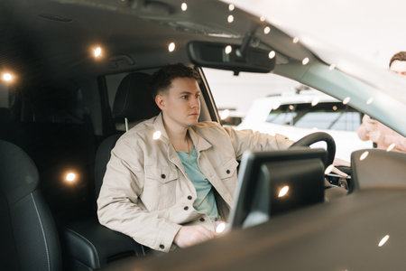 View through windshield of pensive young male customer examine checking auto while sitting behind...