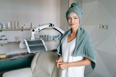 Portrait of pretty beautiful young woman in spa towel standing posing looking at camera after washing hair in beauty salon with casual and relaxed atmosphere. Beauty and hair styling conceptの写真素材
