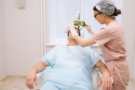 Male patient with hairloss problem prepares to have photodynamic therapy procedure after hair...