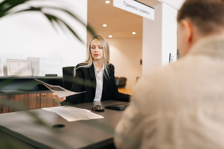 Serious female financial advisor, attorney lawyer or bank manager consulting unrecognizable male client investor receiving document at business meeting, reviewing legal paper file, planning taxes.の写真素材