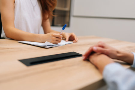 Close-up cropped shot of unrecognizable female team leader listening to employee at meeting. Concentrated woman hr manager holding job interview. Confident businesswoman consulting client.の写真素材