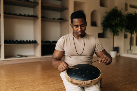 Portrait of calm African man in trance enjoying playing traditional ethnic music on glucophone using...