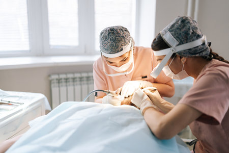 Professional two female trichologist collecting hair follicles from back of head of male patient for hair transplantation in clinic. Process of hair transplant with FUE Sapphire method.の写真素材