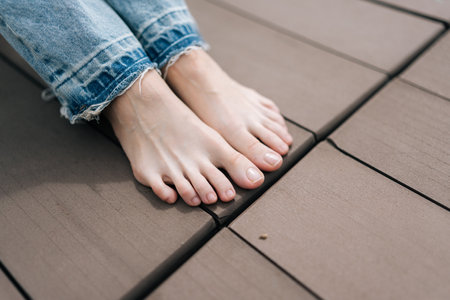 Close-up cropped shot of unrecognizable barefoot female wearing jeans taking moment to relax, bare...