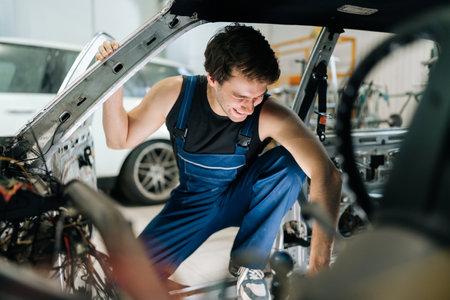 Portrait from interior of old vehicle to smiling mechanic male inspecting car for useful things for secondary repairs before recycling. Concept of professional car repair and maintenance work.の写真素材