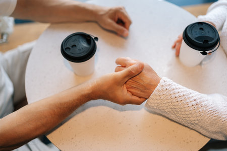 High-angle view of unrecognizable happy elderly couple enjoying each other company having coffee at cafe, demonstrating importance of companionship and connection in later life.の写真素材